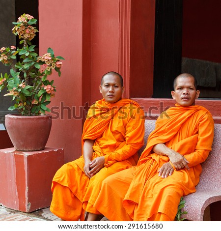 CAMBODIA, PNOM PENH, 2012 - MARCH 26: Young buddist monks wearing orange kasaya robes sitting outdoors in Pnom Penh on March 26, 2012