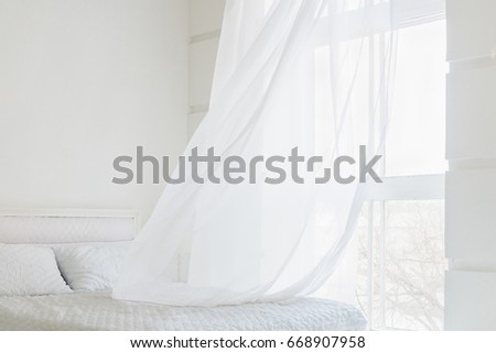 White waving curtain in white bedroom with window