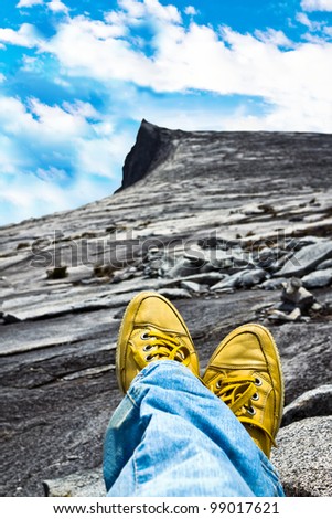 Woman\'s legs relaxing in mountain landscape with clouds