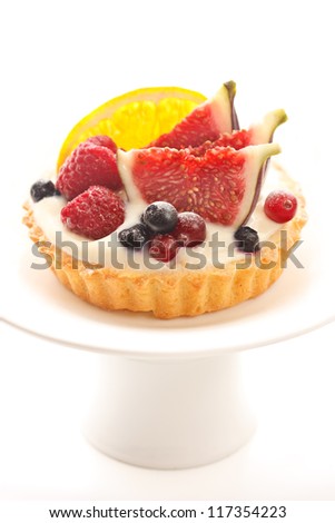 Delicious cake with custard and fresh berries and fruits on a cake stand.