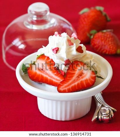 Whipped cream with strawberry on a cake stand.