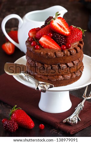Delicious chocolate cake with cream and berries on a cake stand.