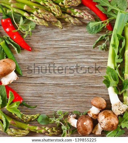 Frame of fresh vegetables and herbs on a wooden background.