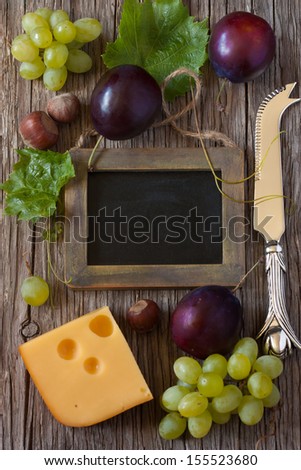 Delicious cheese with fruit and nuts and chalk blackboard for text on a wooden board.