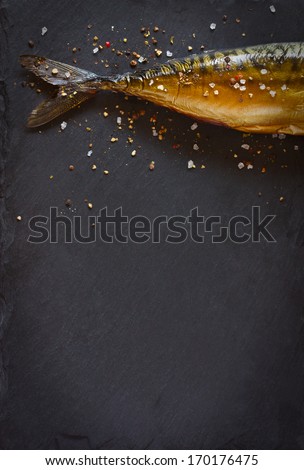 Smoked fish with spices on a black background.