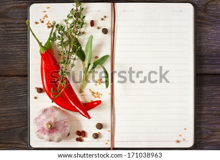 Open Recipe Book With Chili And Spices On A Wooden Background.