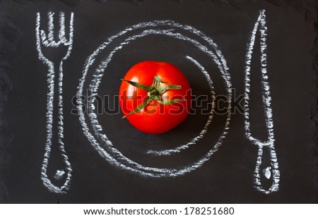 Healthy food concept. Fresh organic tomato on a chalk painted plate.