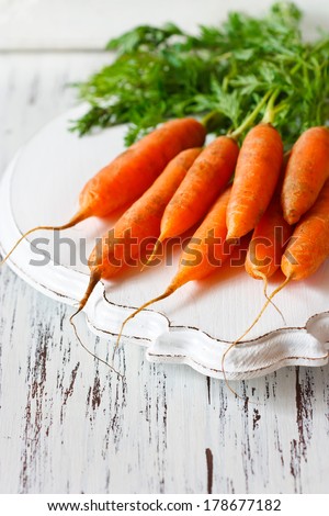 Fresh organic kitchen garden carrots on vintage wooden plate close-up.