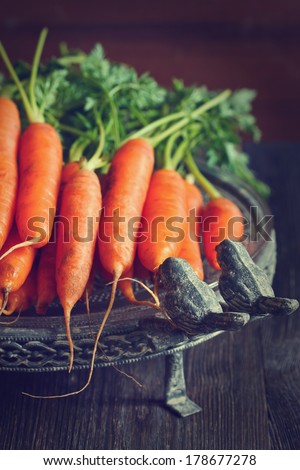 Fresh organic kitchen garden carrots on vintage plate. Toned photo.