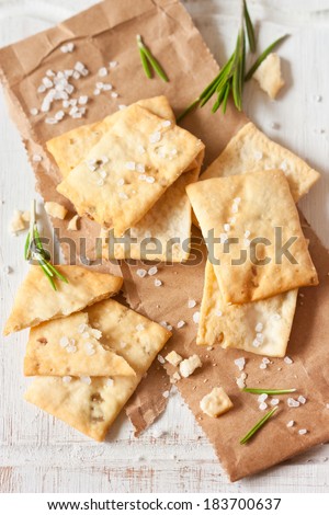 Homemade crackers with rosemary and sea salt for appetizer on an old cooking board.
