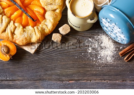 Homemade apricot pie with vanilla and brown sugar on a wooden background with food ingredients for baking.