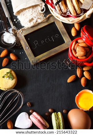 Baking frame. Sweet macarons cookies and food ingtedients for baking on a black slate board with copy space for recipe.