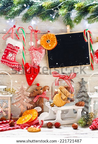 Christmas decorations with cookies in a glass bell jar on a sledge with greeting on chalk blackboard.