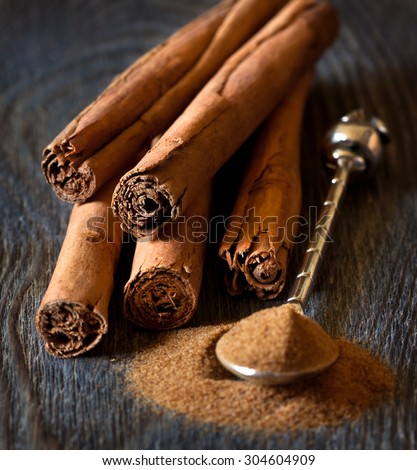 Cinnamon sticks and cinnamon powder on silver spoon close up.
