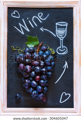 Fresh ripe red grape cluster on old chalk board. Invitation card.