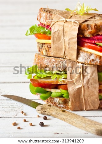 Two delicious sandwiches wrapped in papper and tied with kitchen twine. Selective focus.