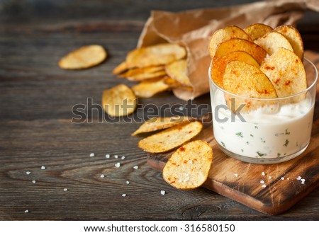 Homemade potato chips and spicy dip served in glass.