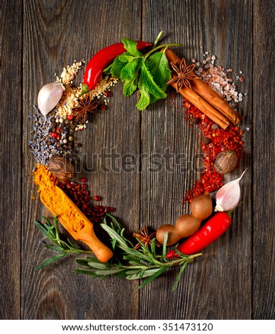 Colorful circle wreath of spices and herbs on wooden table.