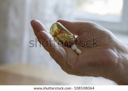 old man holding pills and he needs help