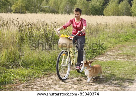 Beautiful girl on the bike and a corgi dog
