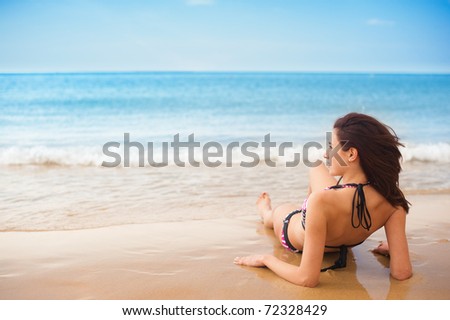 Female Model, Sitting back/Relaxing on Sand, facing sideways to the sea, as waves come in, at the beach.