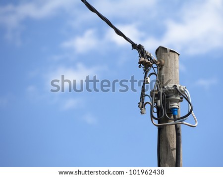 old wooden pole with cables for telephone and power services with blue and cloudy sky