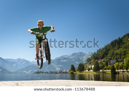 young male teenager jumps high with his dirt bike on a lake base