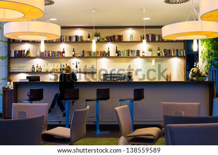 lonely girl sits alone at modern illuminated hotel bar