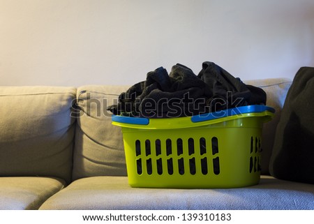 green laundry clothes basket standing couch