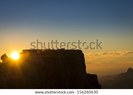 sun shining between rocks on mountain at sunset