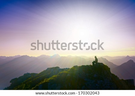 lonely sad girl sitting on mountain summit looking over alps