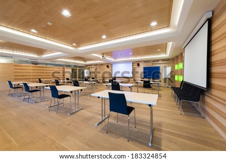 modern wooden conference room with tables an chairs and projector screen