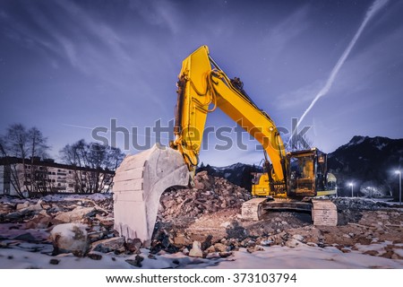 huge orange shovel digger on demolition site at night