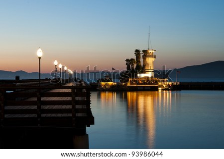 lighted tower beacon with restaurant next to a catwalk at dawn with nice mirroring in the water