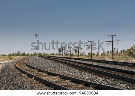 old rails bedded in stones and power poles with blue sky in a desert in arizona