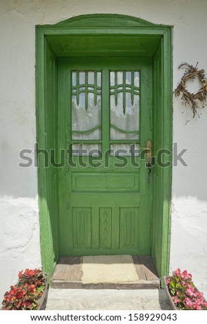 Antique green door with ornaments and keys hanging from the lock