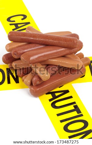 Dietary fast food warning, caution of high cholesterol and saturated fat, unhealthy nutrition concept image (Variety of beef sausages, wieners and hot dogs wrapped in yellow caution tape)