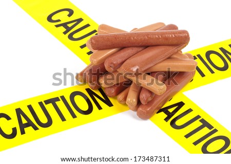 Dietary fast food warning, caution of high cholesterol and saturated fat, unhealthy nutrition concept image (Variety of beef sausages, wieners and hot dogs wrapped in yellow caution tape)