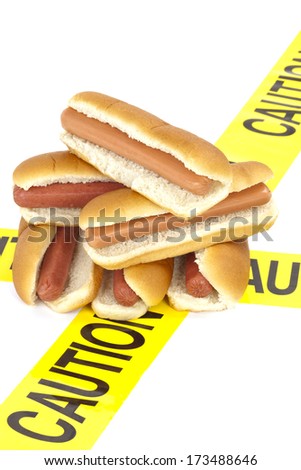 Dietary fast food warning, caution of high cholesterol and saturated fat, unhealthy nutrition concept image (Beef sausages, wieners and hot dogs with buns wrapped in yellow caution tape)