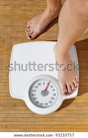 Woman dieting, close up of woman\'s bare feet standing on a weight scale