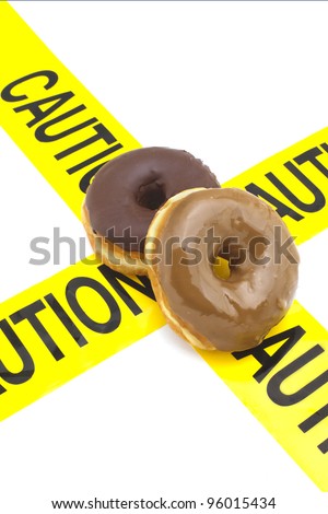 Dietary warning, or high calorie/high, fat junk food warning (donuts placed on top of yellow caution tape)