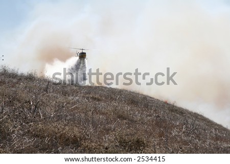 A fire helicopter dropping water on a brush fire