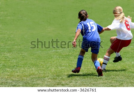 Two girls fighting to get the ball in a soccer game