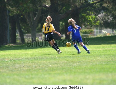 Girls running after a ball playing soccer