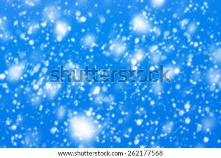 Texture made of snowflakes falling down with the blue sky in the background.