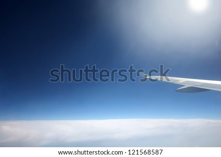 Space sky with aircraft wing. 	View from the plain on white condensed clouds and space above the clouds