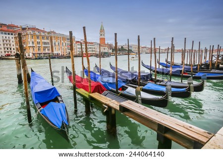 A view of empty gondolas moored and lined up at a gondola dock in a water canal in Venice, Italy.