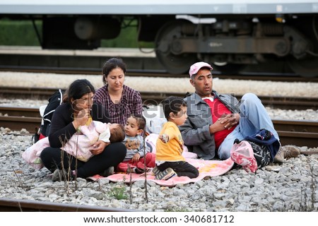 DUGO SELO,CROATIA-SEPTEMBER 17:Syrian refugee family sitting on the train tracks after arriving from Serbia and waiting for the buses to continue the journey on September 17,2015 in Dugo Selo,Croatia.