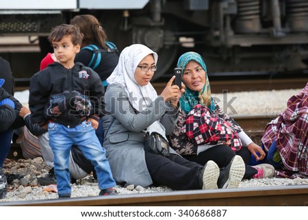 DUGO SELO, CROATIA -SEPTEMBER 17:Syrian woman sitting on ground with other refugees after arriving from Serbia and waiting for buses to continue the journey on September 17, 2015 in Dugo Selo,Croatia.