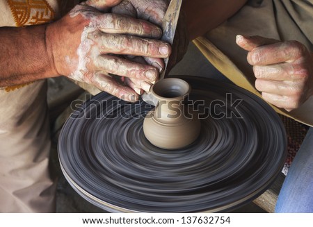 the hands of a potter and a pupil at the potter\'s wheel